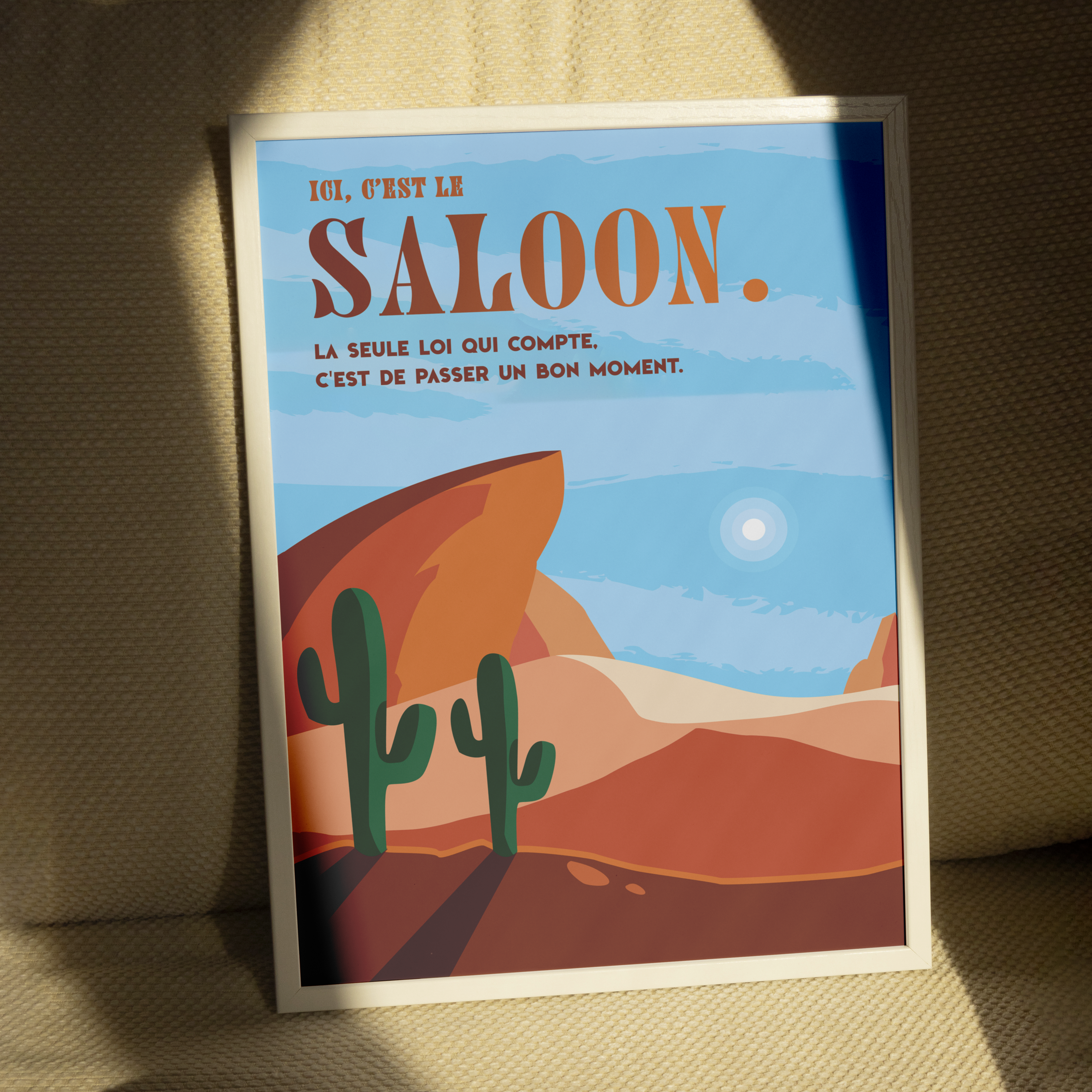 Affiche déco style western avec désert, cactus et rochers rouges, inscription “Ici, c’est le saloon. La seule loi qui compte, c’est de passer un bon moment.”, décoration murale vintage Far West pour salon, bar, bureau ou salle de jeux.