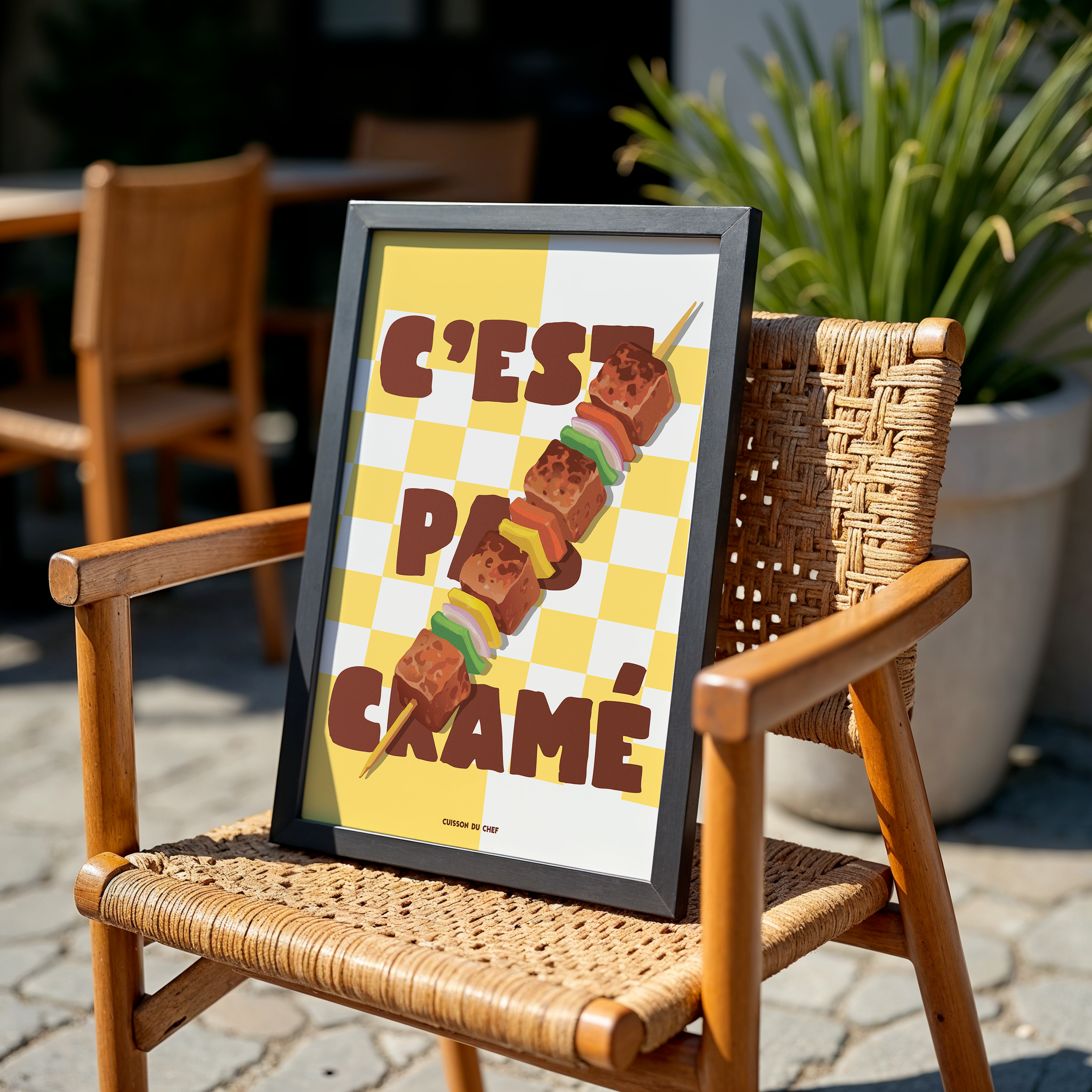 Affiche « C’est pas cramé » : brochette de barbecue en diagonale sur damier jaune, typo brune, déco cuisine humoristique.