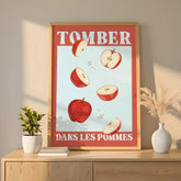 Affiche humoristique “Tomber dans les pommes” représentant plusieurs pommes rouges coupées en morceaux qui semblent flotter ou chuter sur un fond bleu clair. Le texte blanc en majuscules encadré de rouge évoque une expression française populaire. Design minimaliste et coloré, impression sur papier épais mat, parfaite pour une décoration murale moderne, cuisine, salon ou bureau. Style graphique rétro, ambiance lumineuse et joyeuse, typographie vintage élégante.