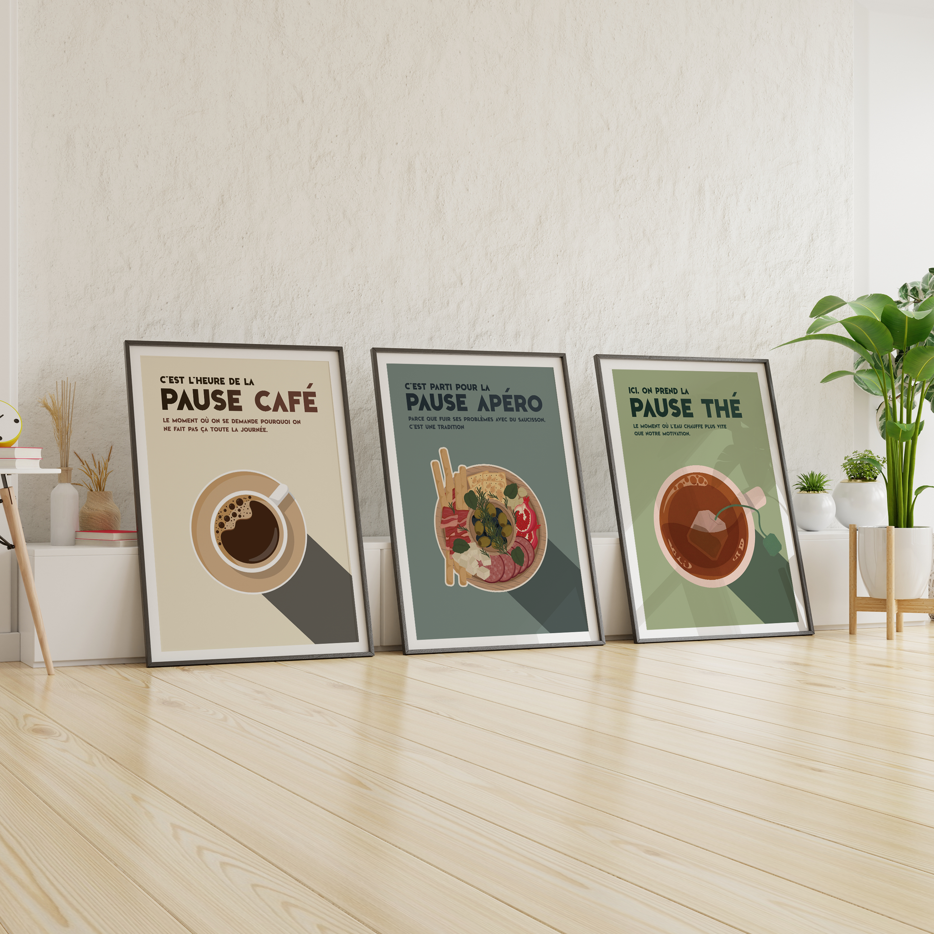 Trois affiches déco humoristiques posées au sol dans un intérieur moderne avec plantes vertes, représentant la pause café, la pause apéro et la pause thé, chacune avec une illustration stylisée et une phrase drôle, parfaites pour cuisine ou salon.