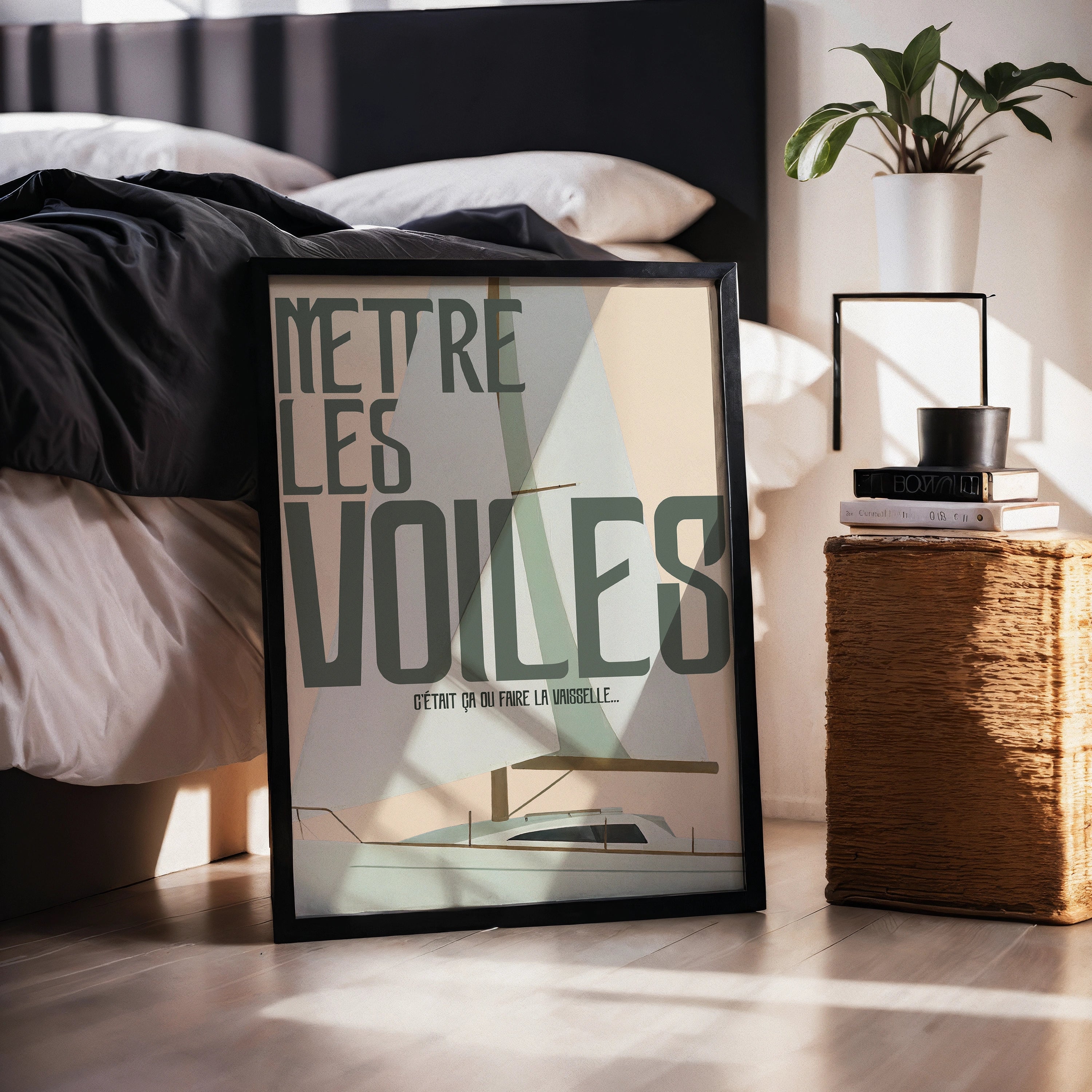 Poster “Mettre les voiles – C’était ça ou faire la vaisselle” dans un cadre noir posé au sol près d’un lit. Illustration minimaliste d’un voilier avec voiles géométriques pastel et lignes fines. Ambiance cosy chambre, lumière douce, plante verte en arrière-plan.